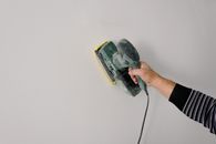 Repairman polishing wall with construction tool
