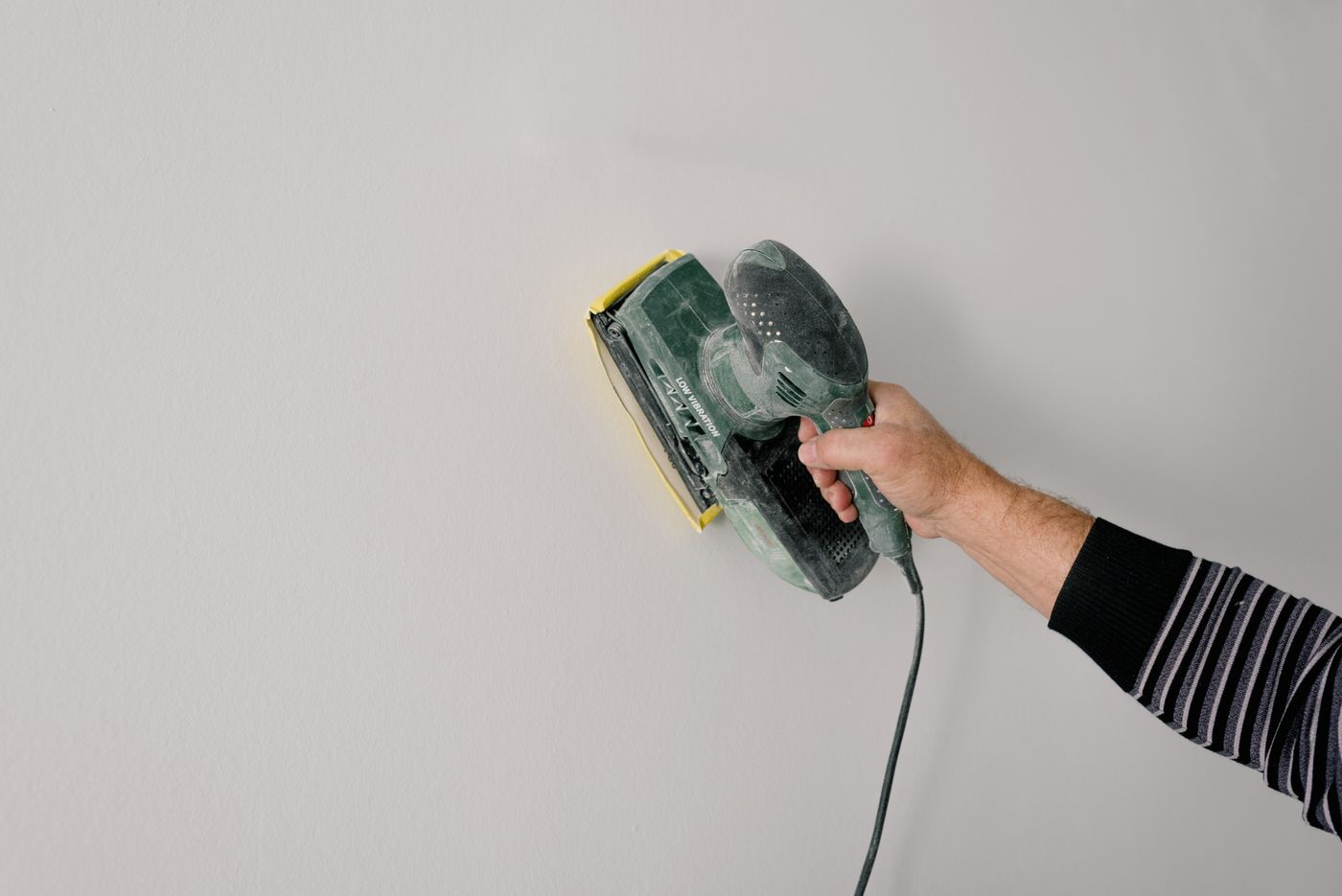 Worker sanding a wall surface during interior repair work