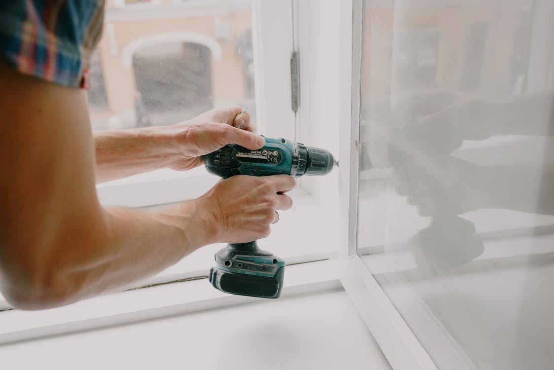 a workman screwing a window frame