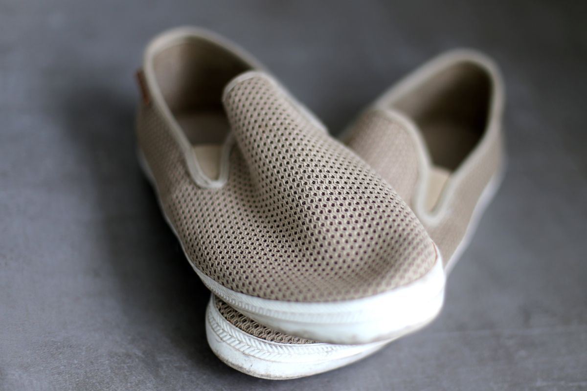 Pair of sand mesh sneakers on a grey studio floor — photo by Amelie W on Pexels