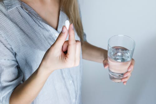 Vrouw Met Halfvol Glas En Witte Medicijnpil