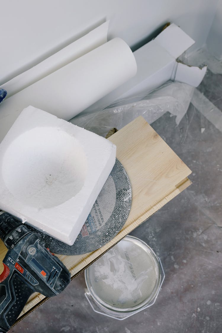 Various Professional Tools And Plywood Plank Placed On Dirty Floor