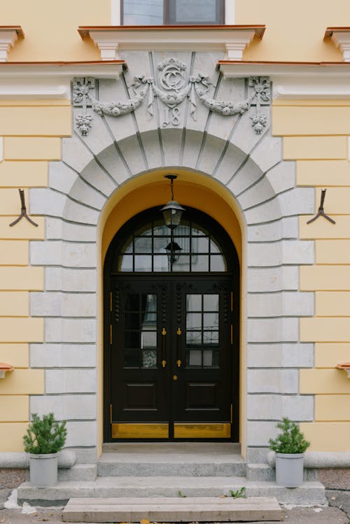 Exterior of classic stone mansion with white and yellow facade decoration around huge entrance wooden arched door