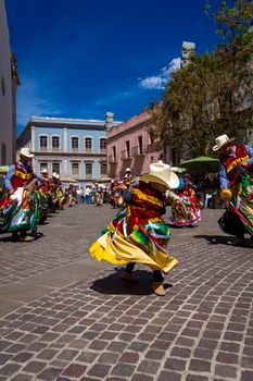 Vibrant Mexican dancers in traditional costumes performing in a lively street festival.