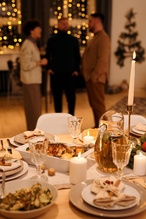 Free Elegant Christmas dinner setup with candles and holiday decor, creating a cozy atmosphere. Stock Photo