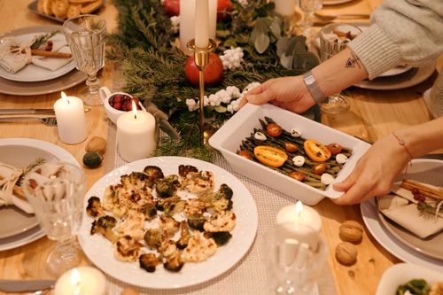 Free A beautifully set holiday dinner table with candles, vegetables, and festive decor. Stock Photo