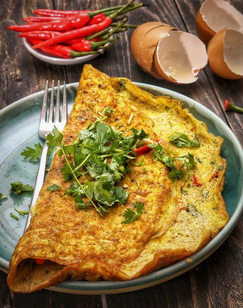 Free Tasty omelette garnished with fresh parsley and chili peppers on a ceramic plate. Stock Photo