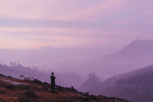 黄昏时分，一个人影俯瞰着美丽的山地景观，天空充满活力