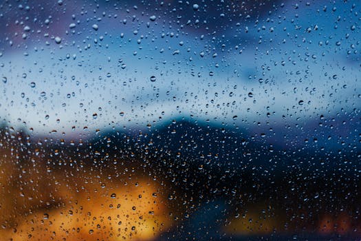 Raindrops on a window with blurred evening lights, showcasing atmospheric beauty.