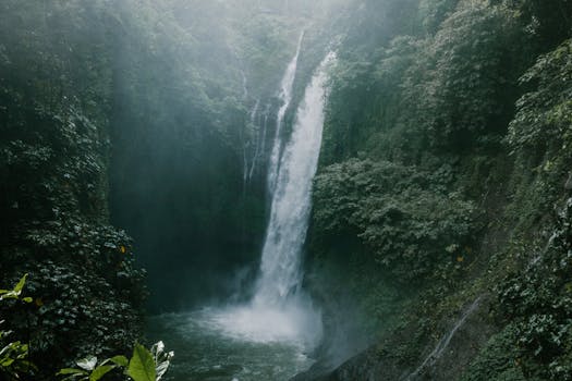 A tranquil waterfall cascading in a verdant jungle setting, surrounded by mist and lush greenery.