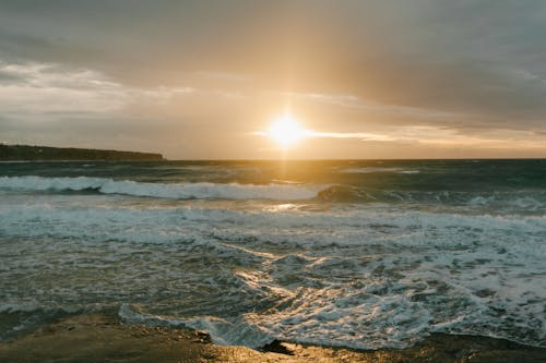 Gratis Gelombang Laut Menabrak Pantai Saat Matahari Terbenam Foto Stok