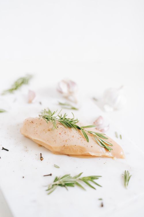 Free A raw chicken breast garnished with rosemary sprigs, ideal for culinary projects. Stock Photo