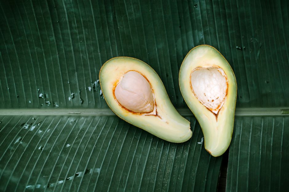 Fresh avocado halves displayed on a banana leaf, highlighting their nutritional value and vibrant color.