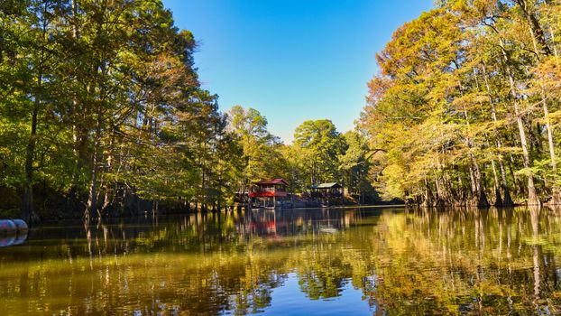 Tranquil tree-lined lake reflecting fall colors in Texas countryside.