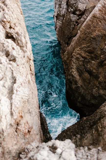 Stunning view of big rocks framing blue water crashing below, showcasing natural beauty.
