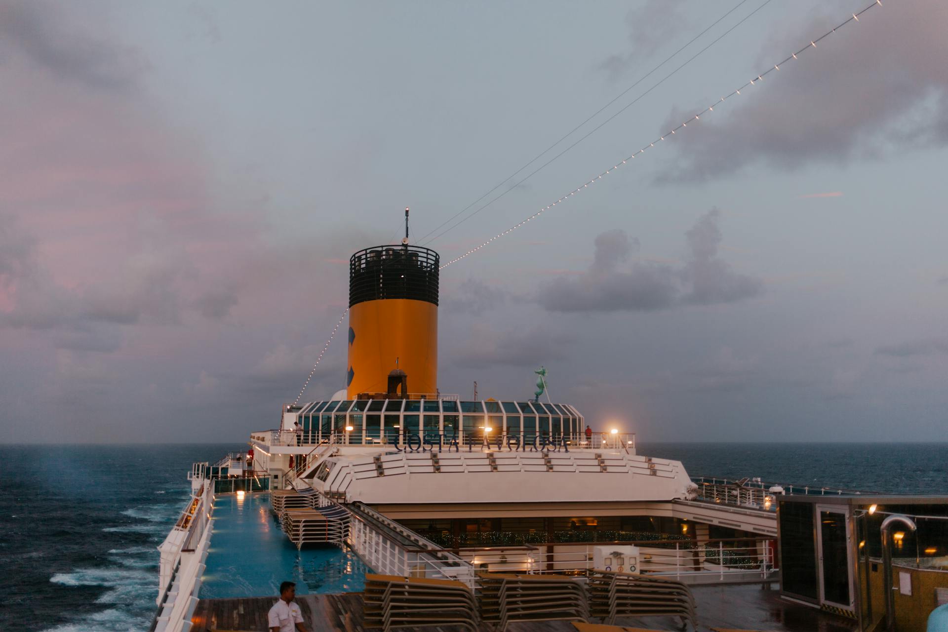 A cruise ship sails peacefully at twilight, with a beautiful ocean backdrop and soft evening lights.