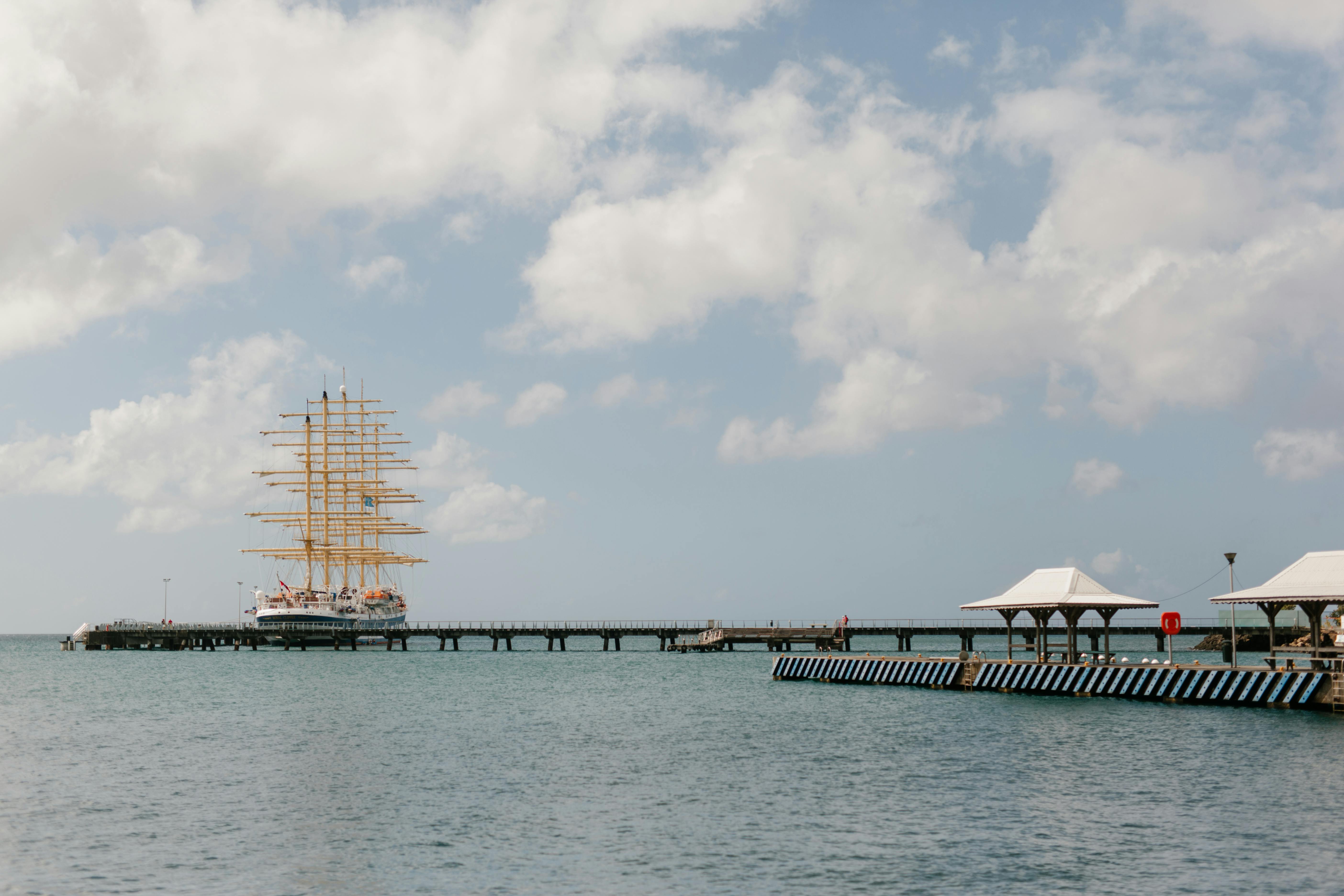 一艘雄伟的高船停泊在蓝天下的木制码头，营造出一片宁静的海景