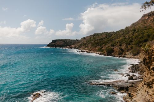 Free Breathtaking view of a rocky coastline with calm turquoise waters and a blue sky above. Stock Photo
