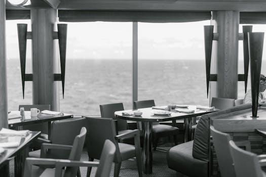 Black and white interior of a seaside restaurant featuring stylish decor and ocean views.