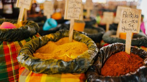 Colorful spices and seasonings on display at a vibrant outdoor market, featuring paprika and other assorted flavors.