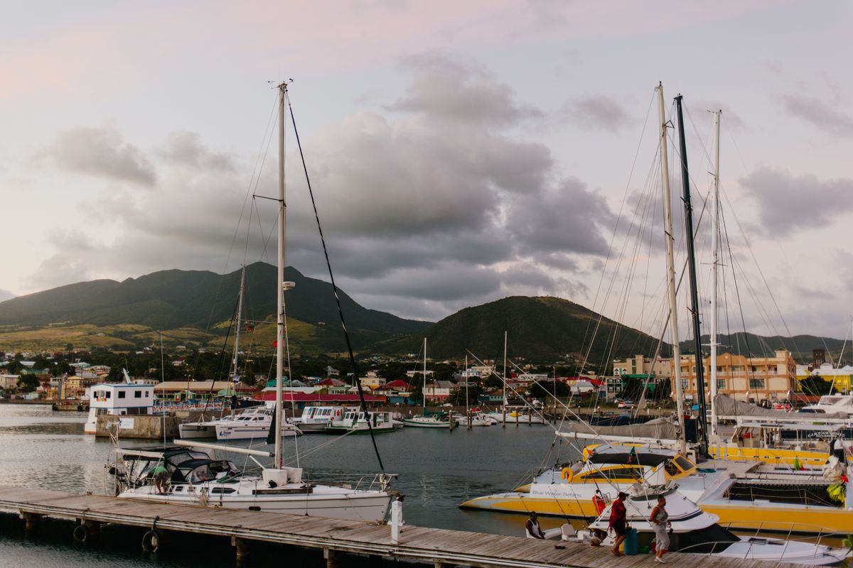 Beautiful marina with sailboats and stunning mountain backdrop at sunset.