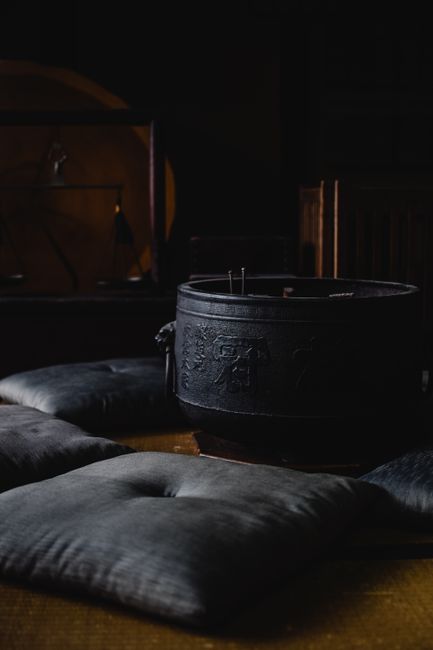 Dimly lit traditional Japanese room with cushions and pot in Kyoto, Japan.