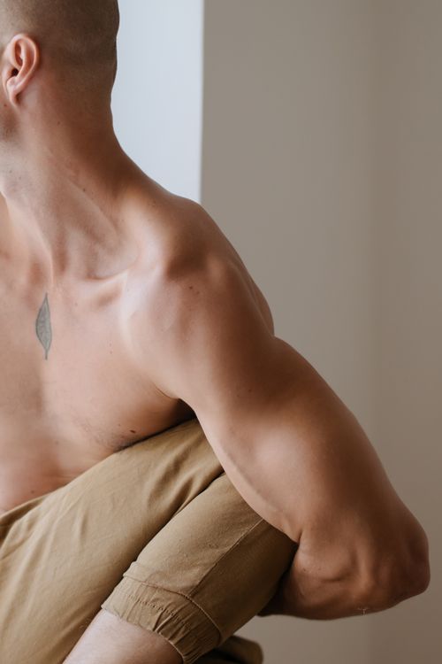 Free Close-up of a man demonstrating acro yoga, showcasing muscular arm and back flexibility indoors. Stock Photo