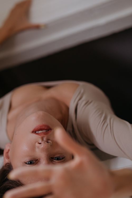 Free Artistic and intimate portrait of a woman lying down, captured in soft lighting with a gentle expression. Stock Photo