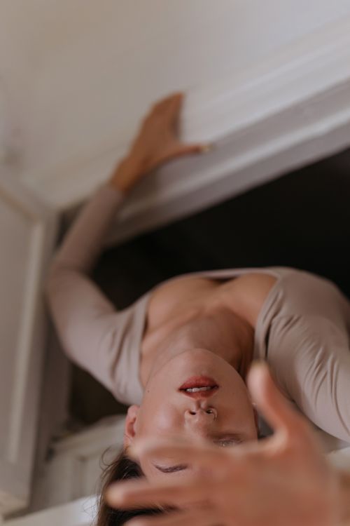 Free A captivating artistic portrait of a woman in a reaching pose, embodying movement and grace. Stock Photo