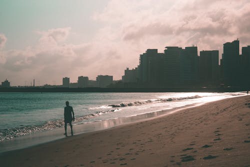 Silhouette of a Man Walking on the Sandy Shore of a Beach