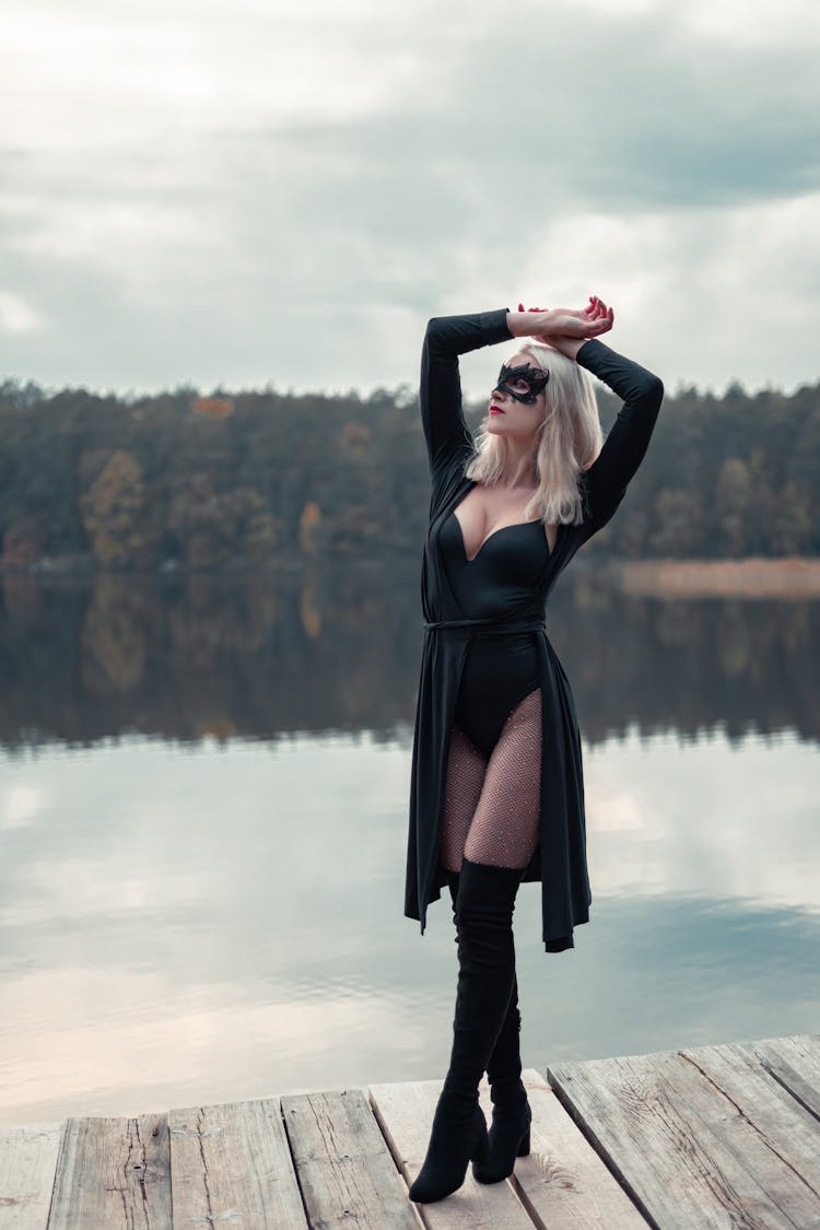 Sensual Model In Decorative Mask On Pier Near River