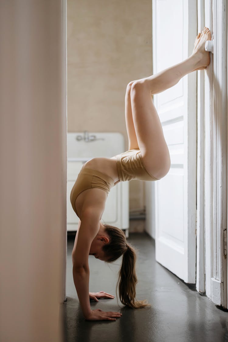 A Woman In Beige Active Wearing Doing Acrobatic Yoga