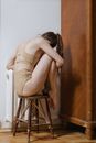Woman Sitting in Fetus Position on a Brown Wooden Chair
