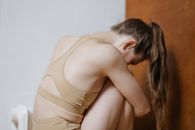 一位穿着米色运动服的年轻女子在室内静坐沉思，捕捉着宁静的时刻