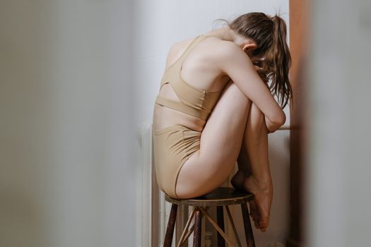一位身着运动服的女人优雅地坐在木凳上，周身散发着柔韧与力量