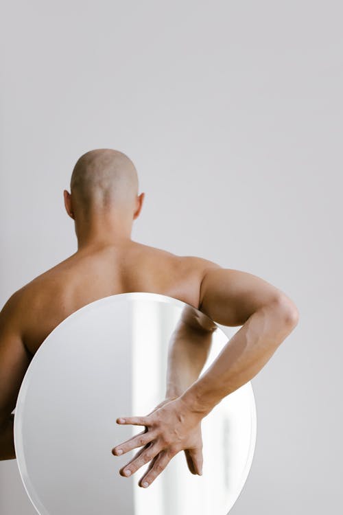 Free Topless Man Holding White Round Mirror from His Back Stock Photo