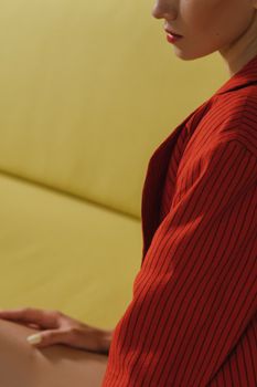Close-up portrait of a woman in a red blazer against a yellow couch.