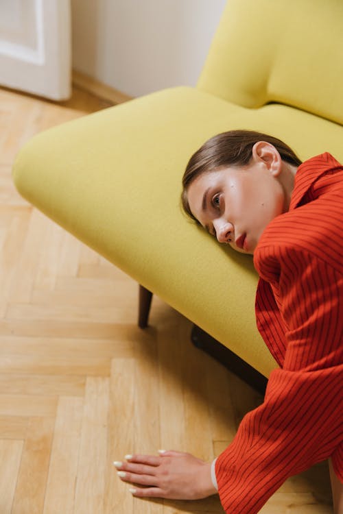 Free Sad Woman in Red Blazer Lying on a Couch Stock Photo