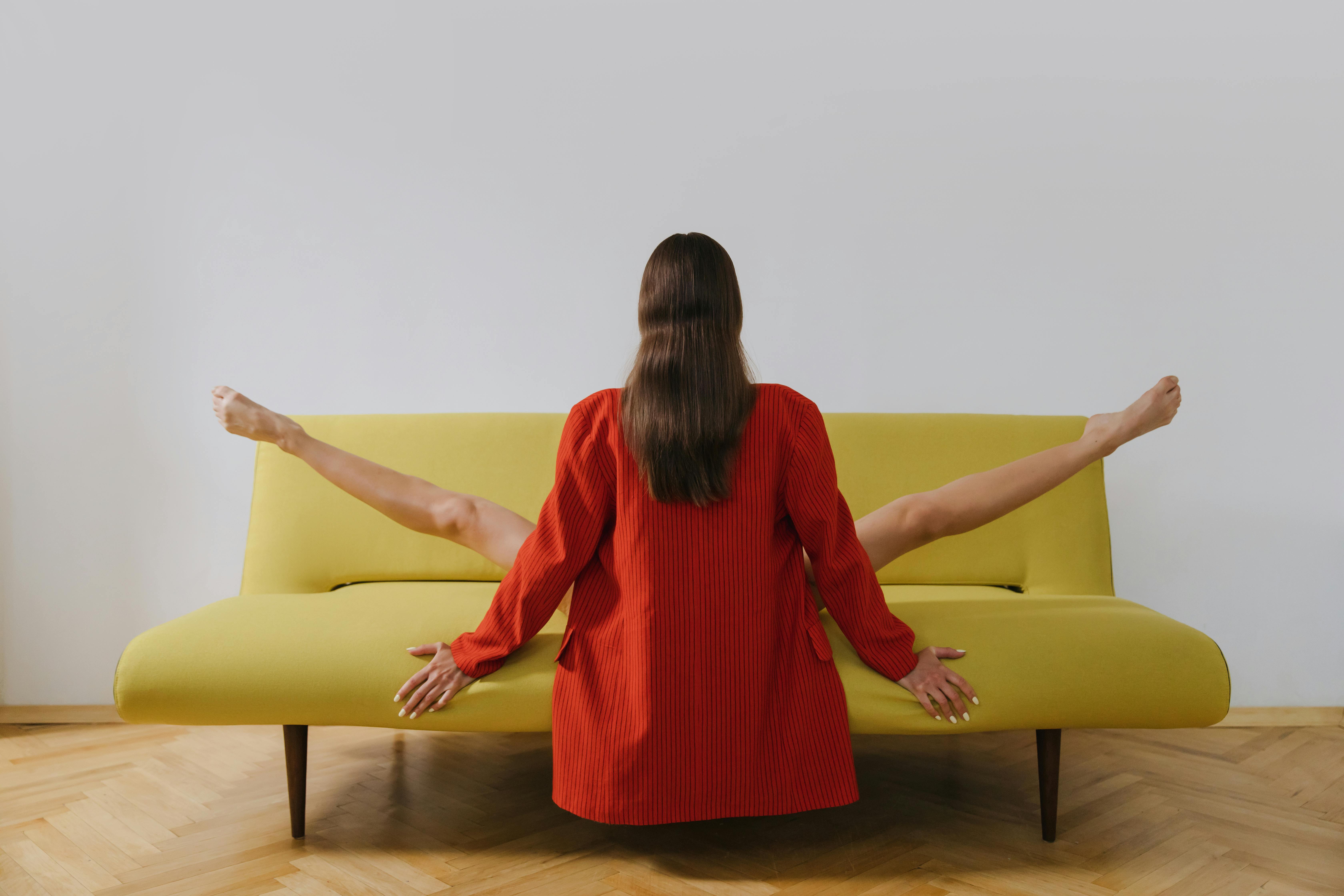 Back View Shot of a Woman Stretching Her Legs while Sitting on a Couch