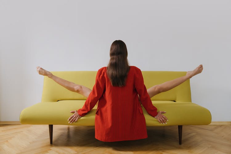 Back View Shot Of A Woman Stretching Her Legs While Sitting On A Couch