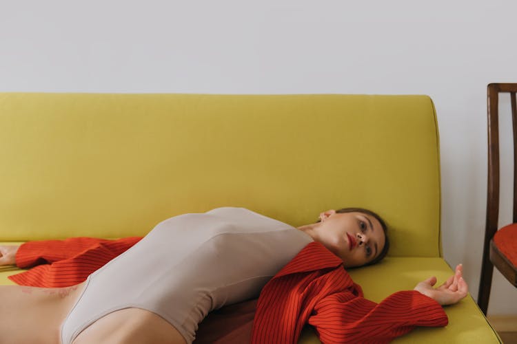 A Tired Woman In Gray Bodysuit And Red Blazer Lying On A Couch