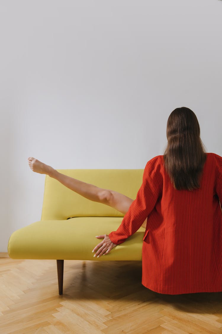 Close-up Shot Of A Woman Sitting On A Couch While Stretching Her Leg