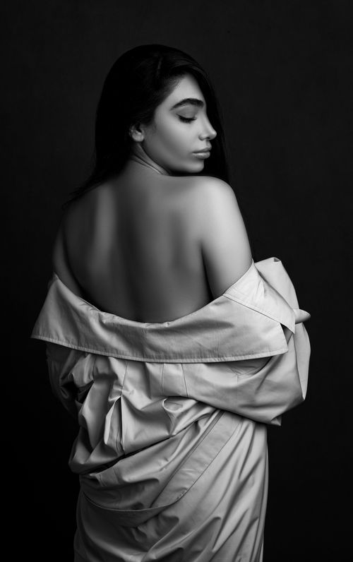Free Artistic black and white portrait of a woman with eyes closed, draped shirt, studio setting. Stock Photo