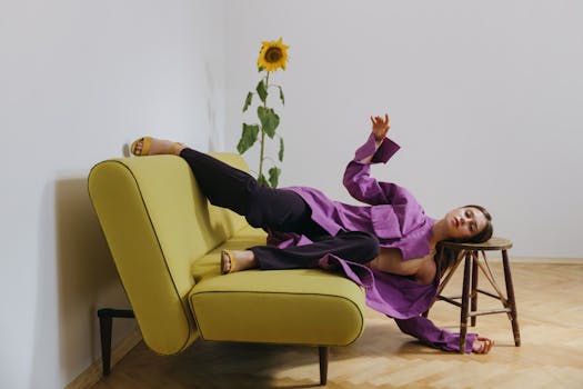 Stylish woman in purple reclining on yellow couch with sunflower accent.