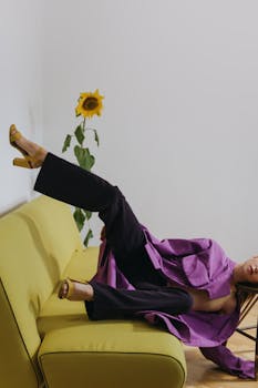 穿紫色外套的女人富有创意地躺在向日葵图案的绿色沙发上