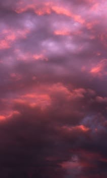 黄昏时分，多云天空呈现出戏剧性的紫色和红色，这张惊人的垂直拍摄照片非常适合用作移动壁纸