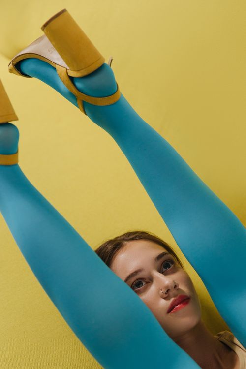 Free Creative fashion portrait featuring a woman in colorful tights and heels against a yellow background. Stock Photo