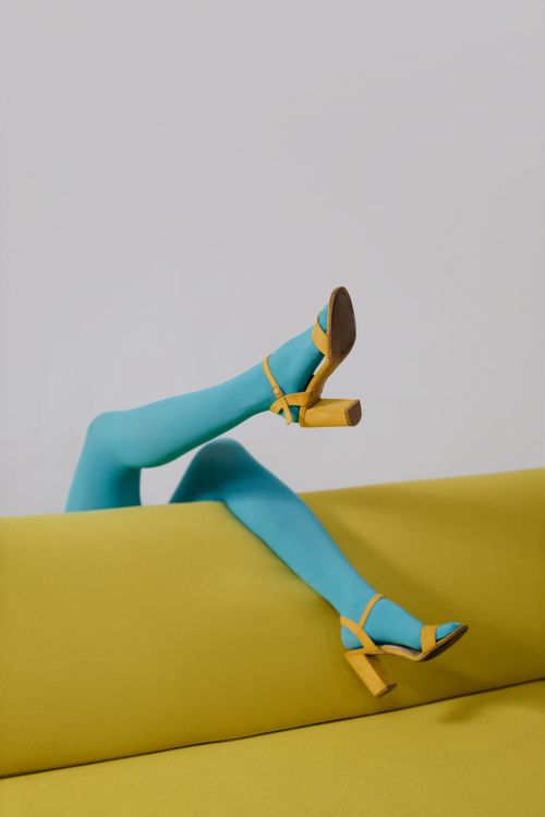 Free Stylish legs in blue tights and yellow heels on a yellow couch, modern fashion. Stock Photo