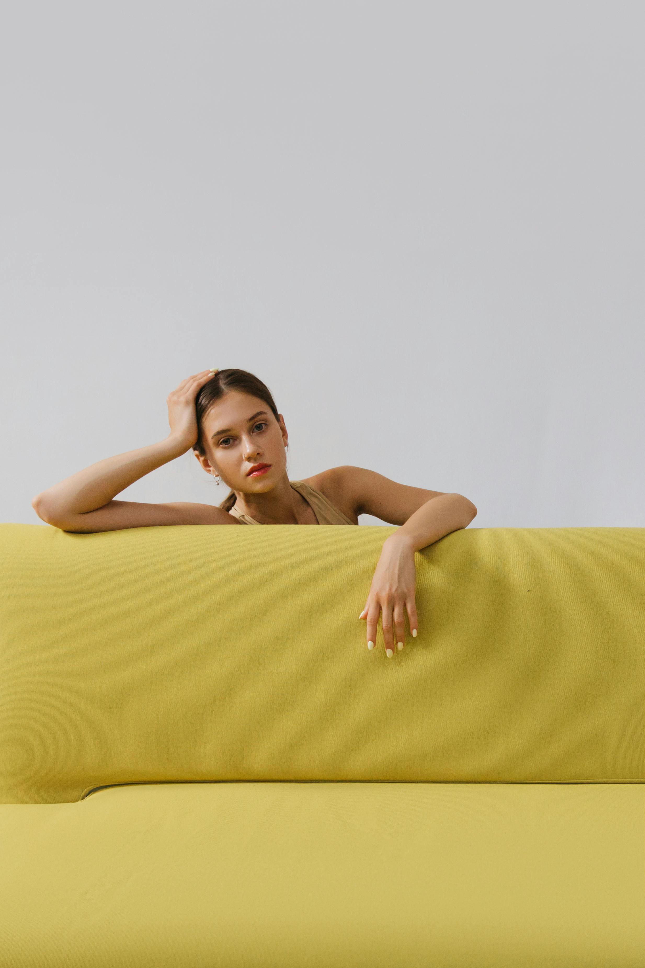 woman leaning on a yellow sofa