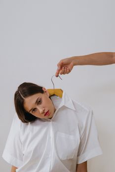 Artistic conceptual photo of a woman wearing a white shirt on a clothes hanger, symbolizing detachment.